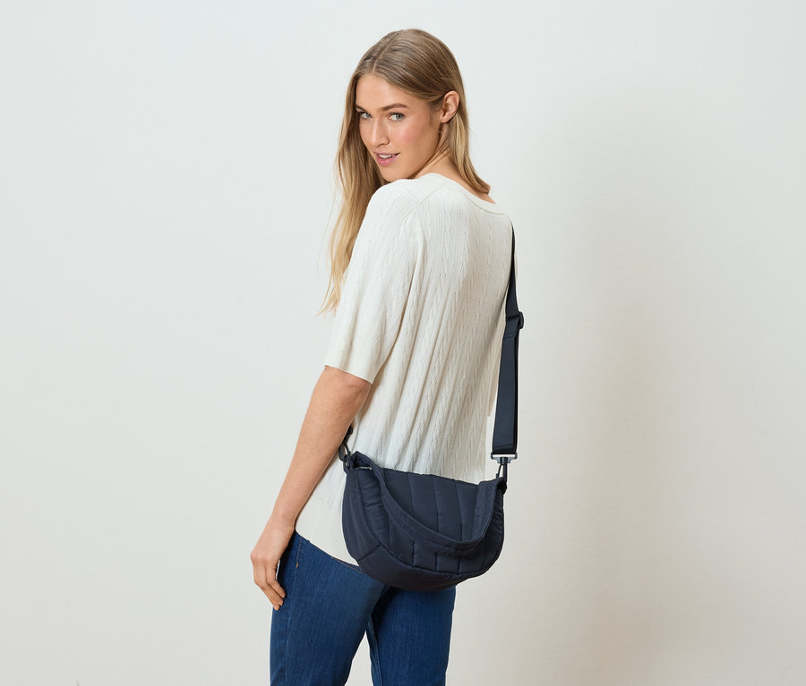 Frau blickt über ihre Schulter und trägt eine marineblaue Umhängetasche.