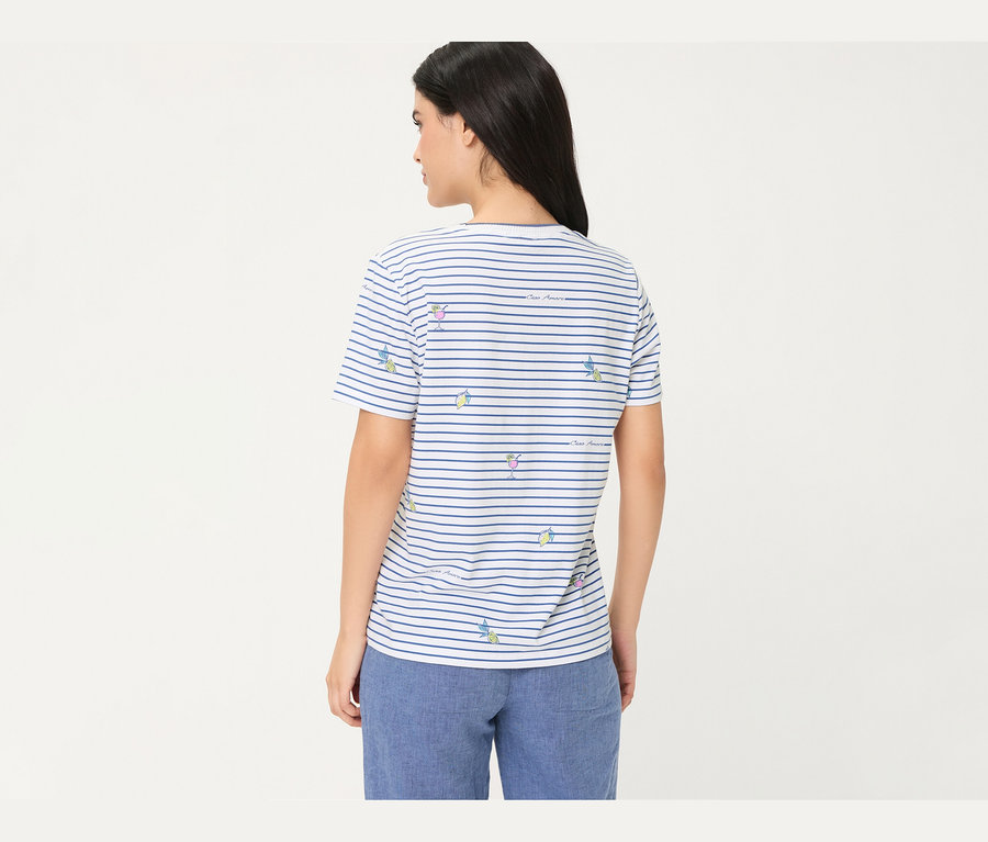 Frau von hinten, die ein weiß-blau gestreiftes Olsen T-Shirt mit Cocktail- und Zitronenmotiven sowie blaue Hosen trägt.