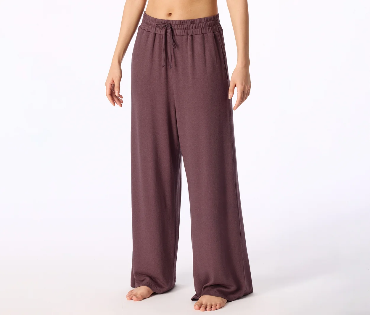 Barfüßige Person trägt dunkelviolette weite Hose mit Kordelzug in der Taille.