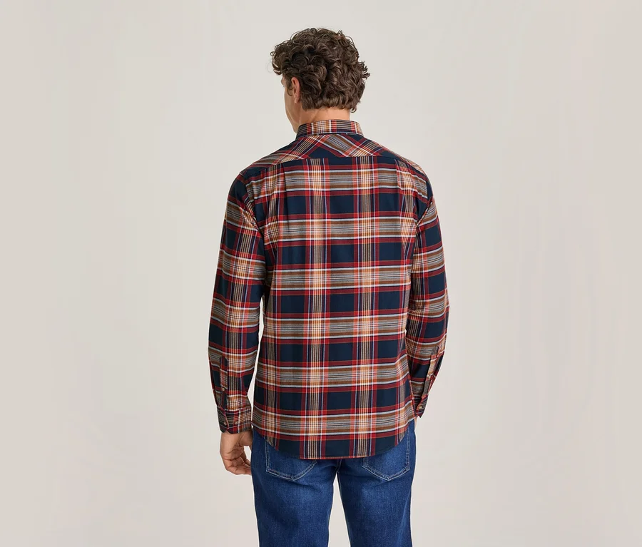 Mann von hinten in einem dunkelblauen, rot-orange-weiß karierten Hemd und blauen Jeans.