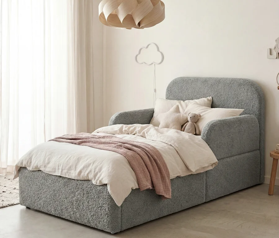 Graues strukturiertes Kinderbett mit heller Bettwäsche, rosa Decke, Teddybär und Sternkissen. Darüber eine Wolken-Wandleuchte und Holz-Pendelleuchte.