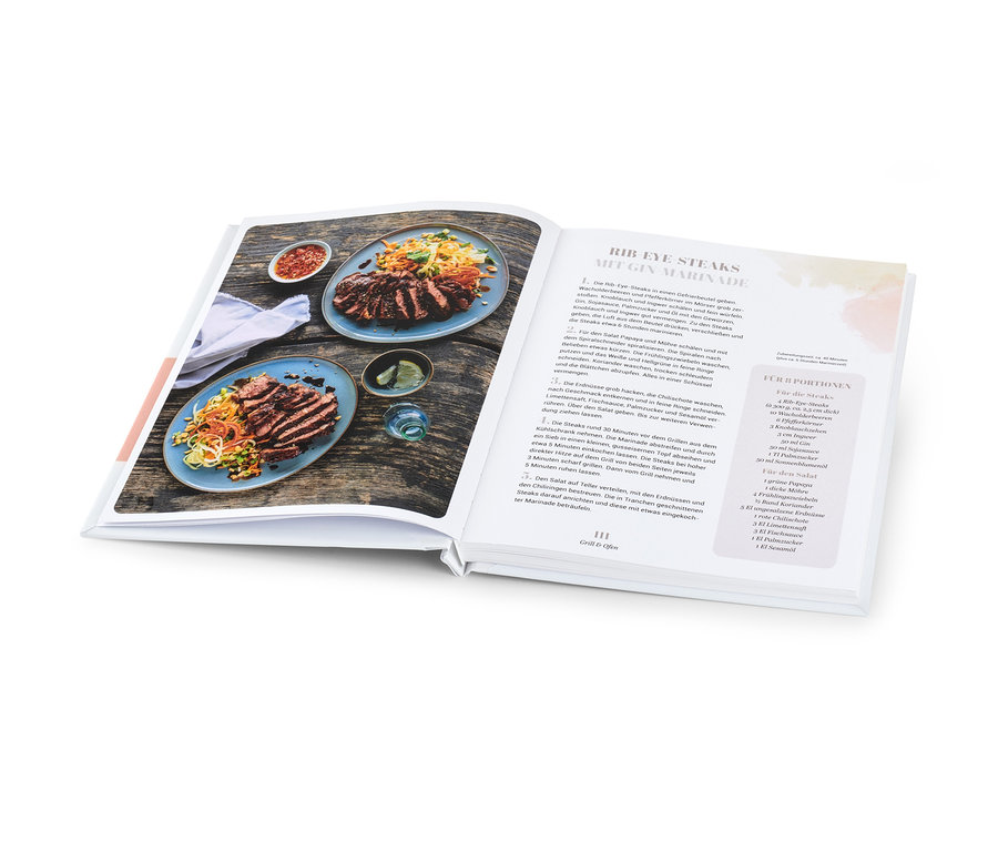 Aufgeschlagenes Kochbuch mit zwei Tellern mit aufgeschnittenem Steak und Salat neben einer Schüssel mit Sauce. Abgebildet ist das Buch »Sommerküche«.