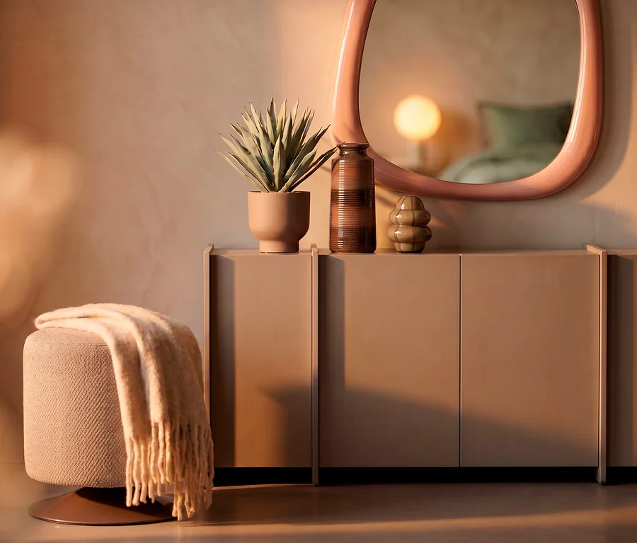 Beige Wohndecke »PLENTY« auf einem runden Hocker neben einem Sideboard mit Pflanze, Vase und Dekoobjekt. Ein rosa Spiegel reflektiert einen Raum mit Lampe.