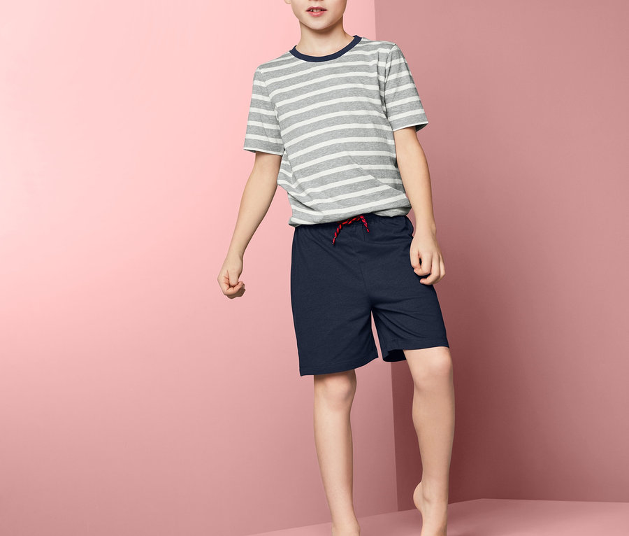 Junge steht auf einem rosa Podest und trägt einen Jungen-Shorty-Pyjama.
