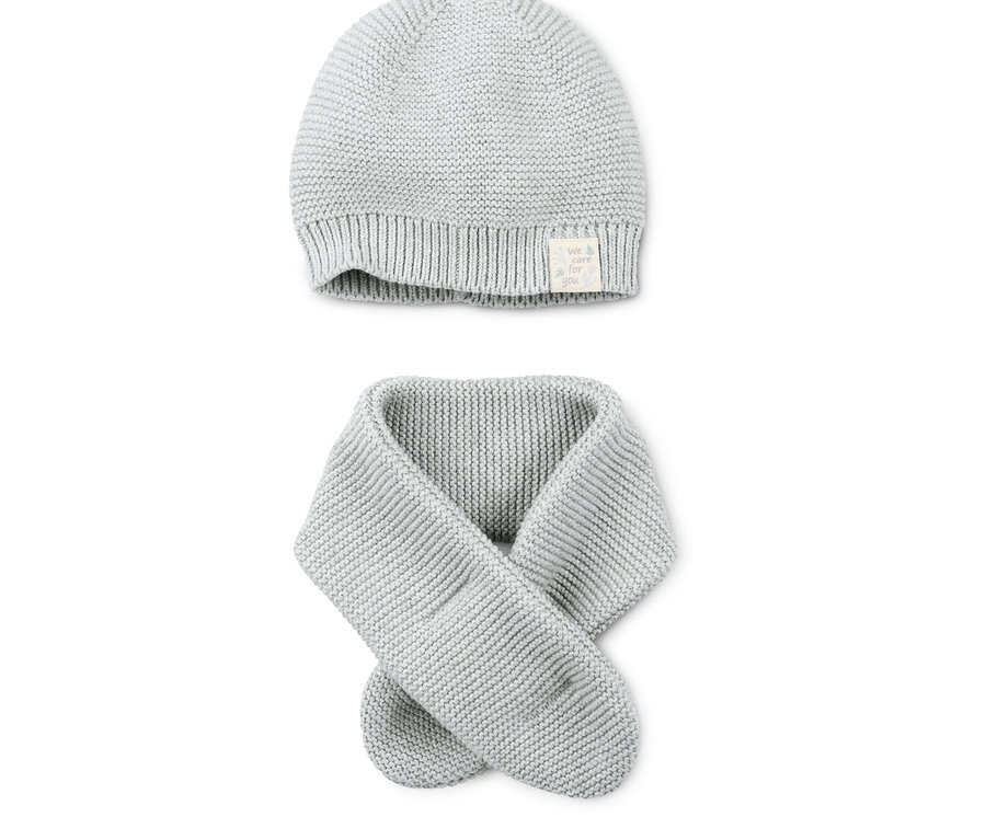 Eine graue Strickmütze und ein Strickschal liegen auf einem weißen Hintergrund.