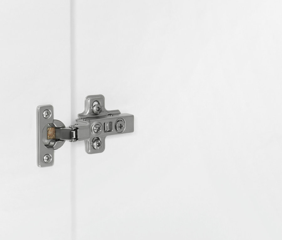 Detail eines silbernen Scharniers an einem weißen Schrank.