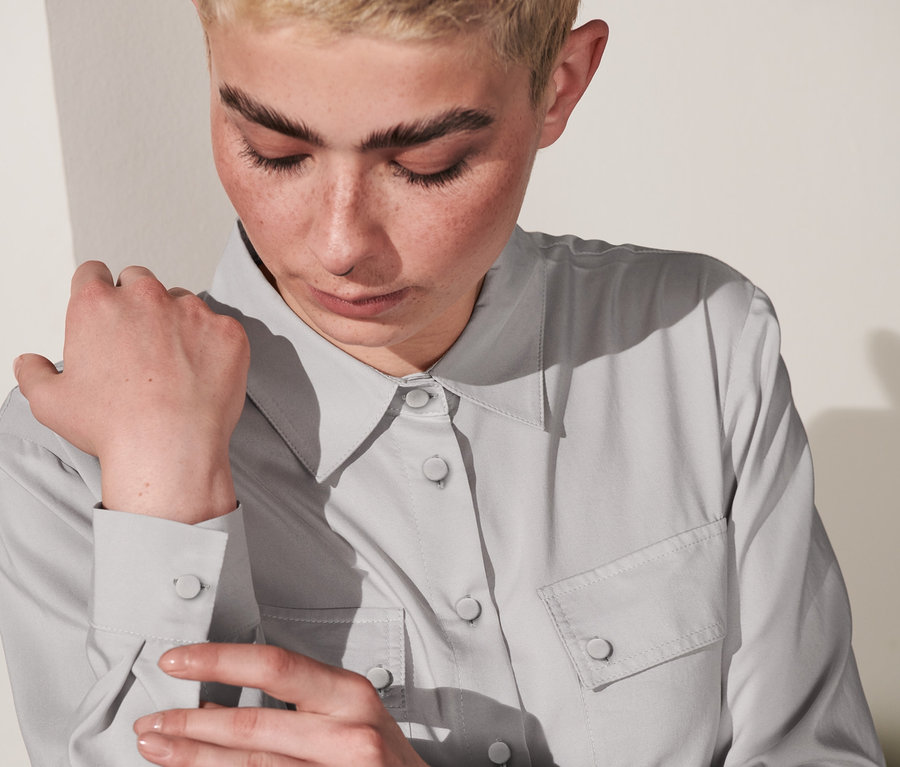 Frau schließt den Ärmel einer Hemdbluse.