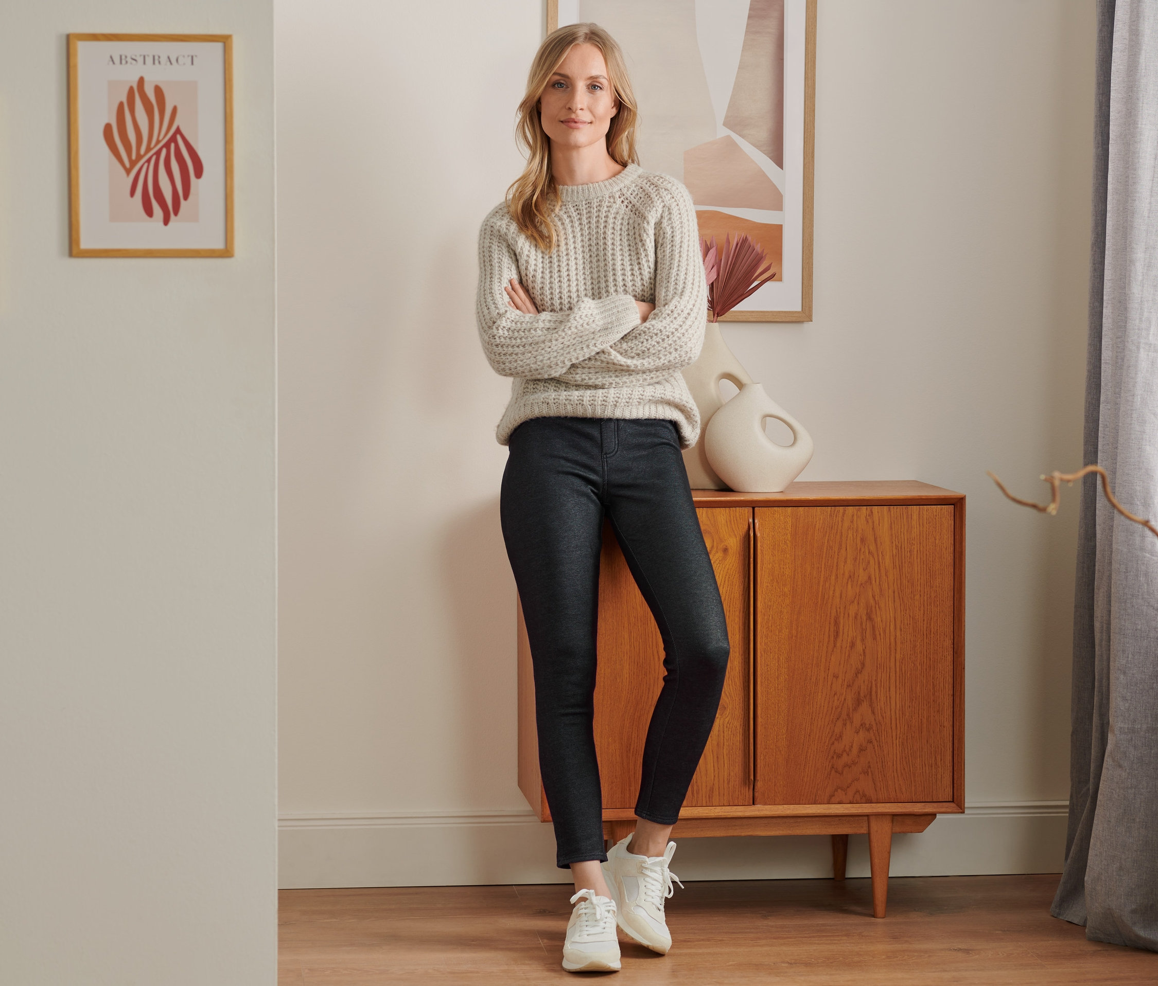 Eine Frau steht mit verschränkten Armen und trägt eine gefütterte Leggings in Jeansoptik, black denim.