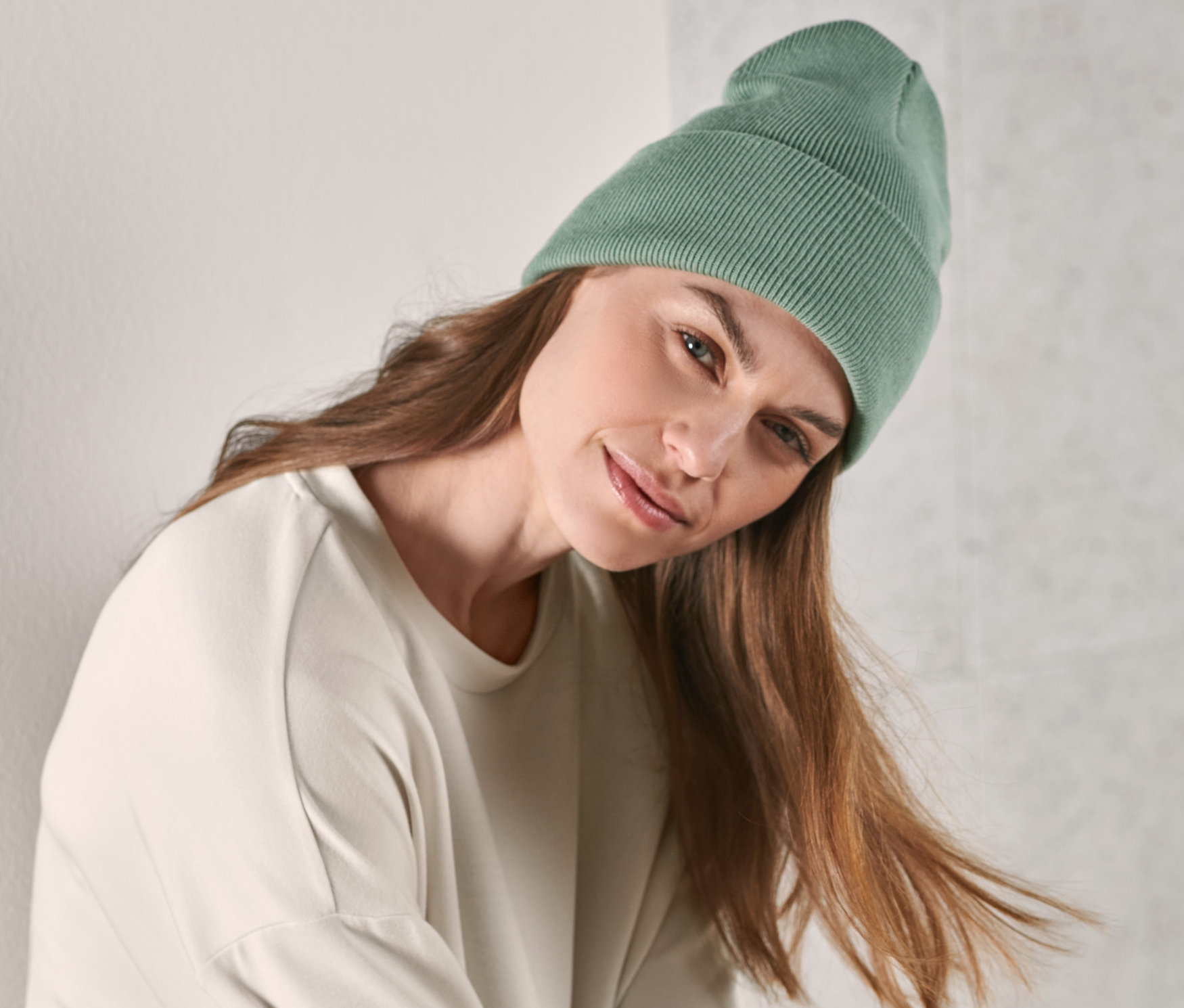 Frau mit braunen Haaren trägt eine hellgrüne Strickmütze.
