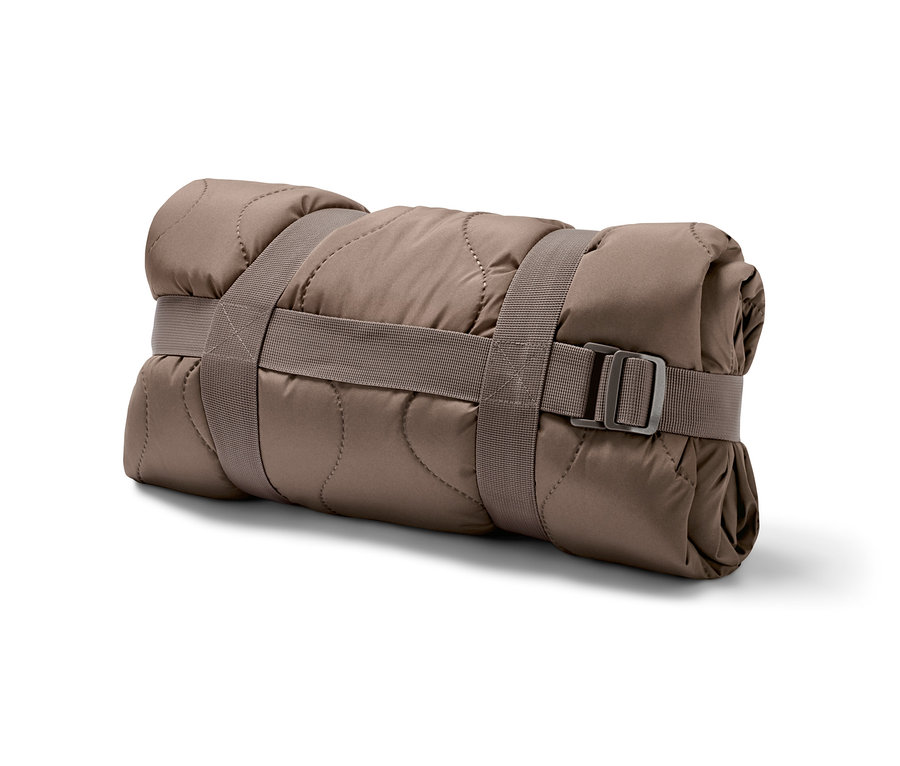 Eine zusammengerollte Outdoor-Thermodecke, die mit Gurten befestigt ist.
