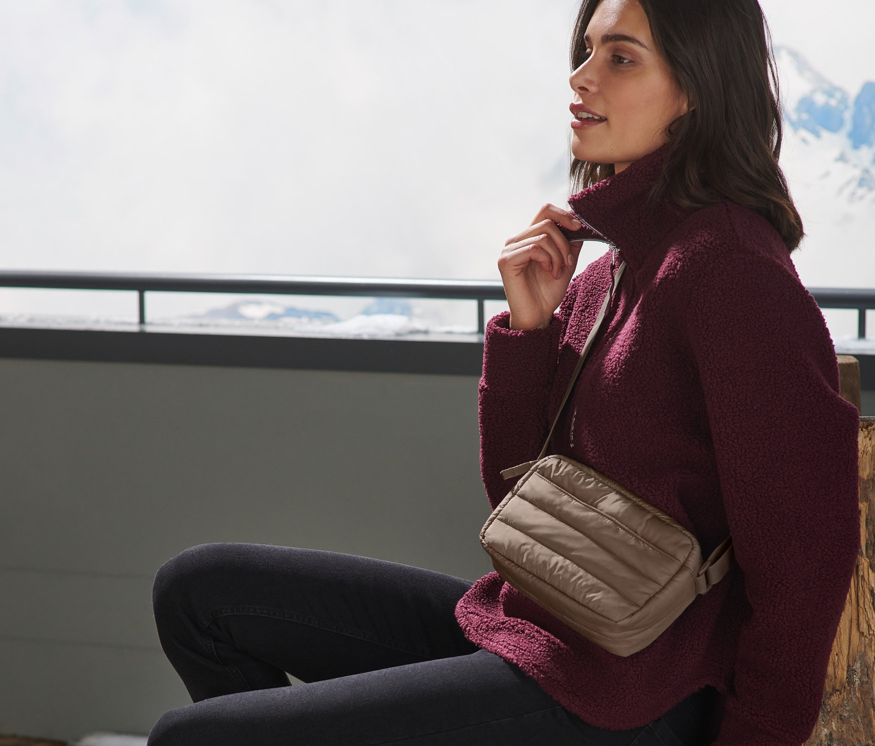 Eine Frau sitzt und trägt eine gesteppte Umhängetasche.