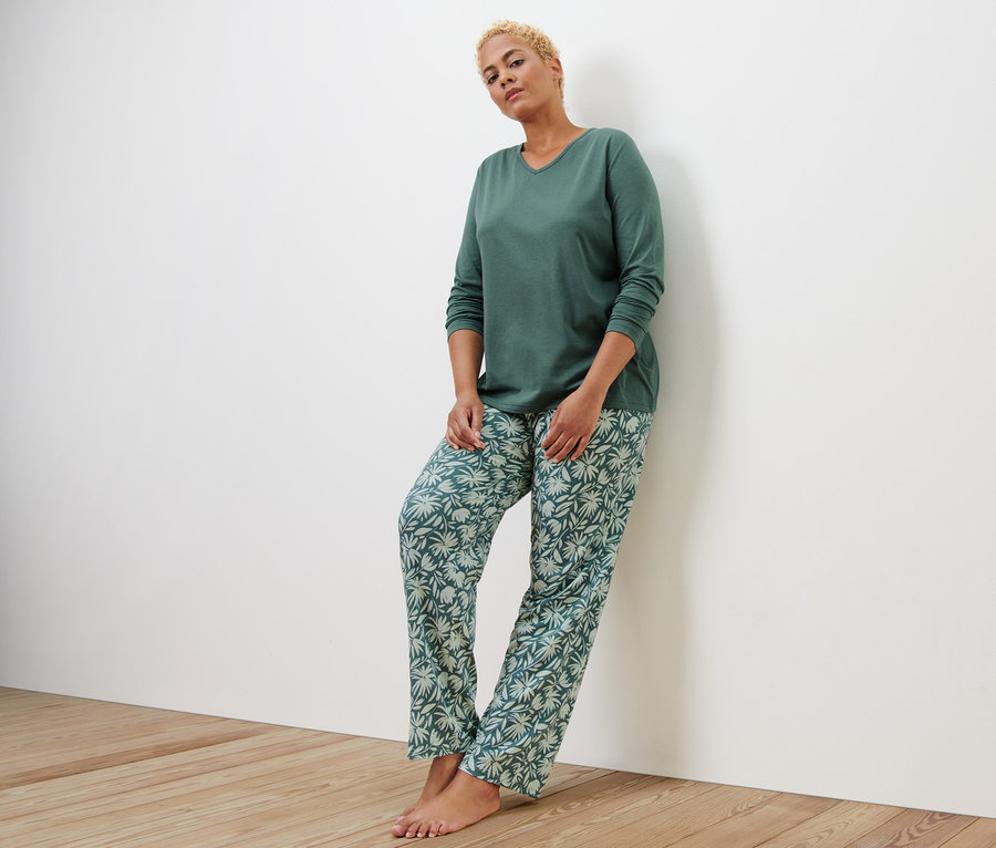 Frau an Wand angelehnt trägt Pyjama.
