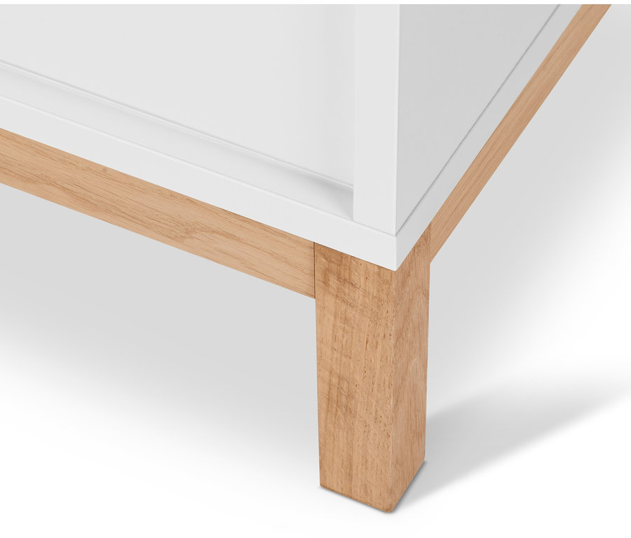 Detailaufnahme eines weißen Waschbeckenunterschranks »Eklund« mit zwei Schiebetüren und Holzfüßen.