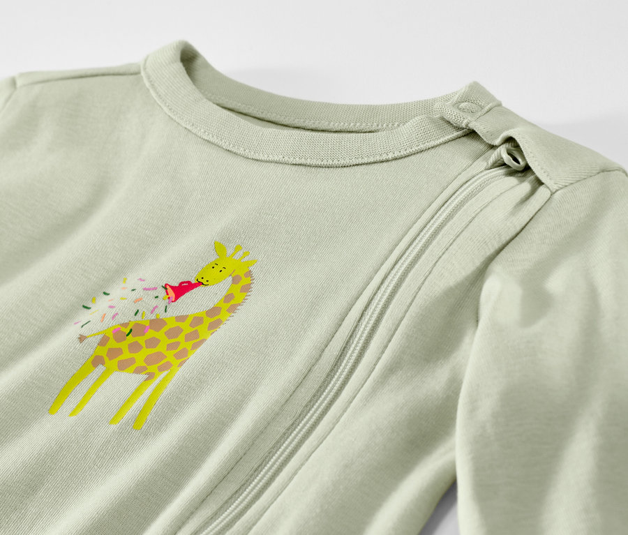 Detailansicht eines hellgrünen Baby-Schlafanzugs mit einer Giraffe mit Partyhut.