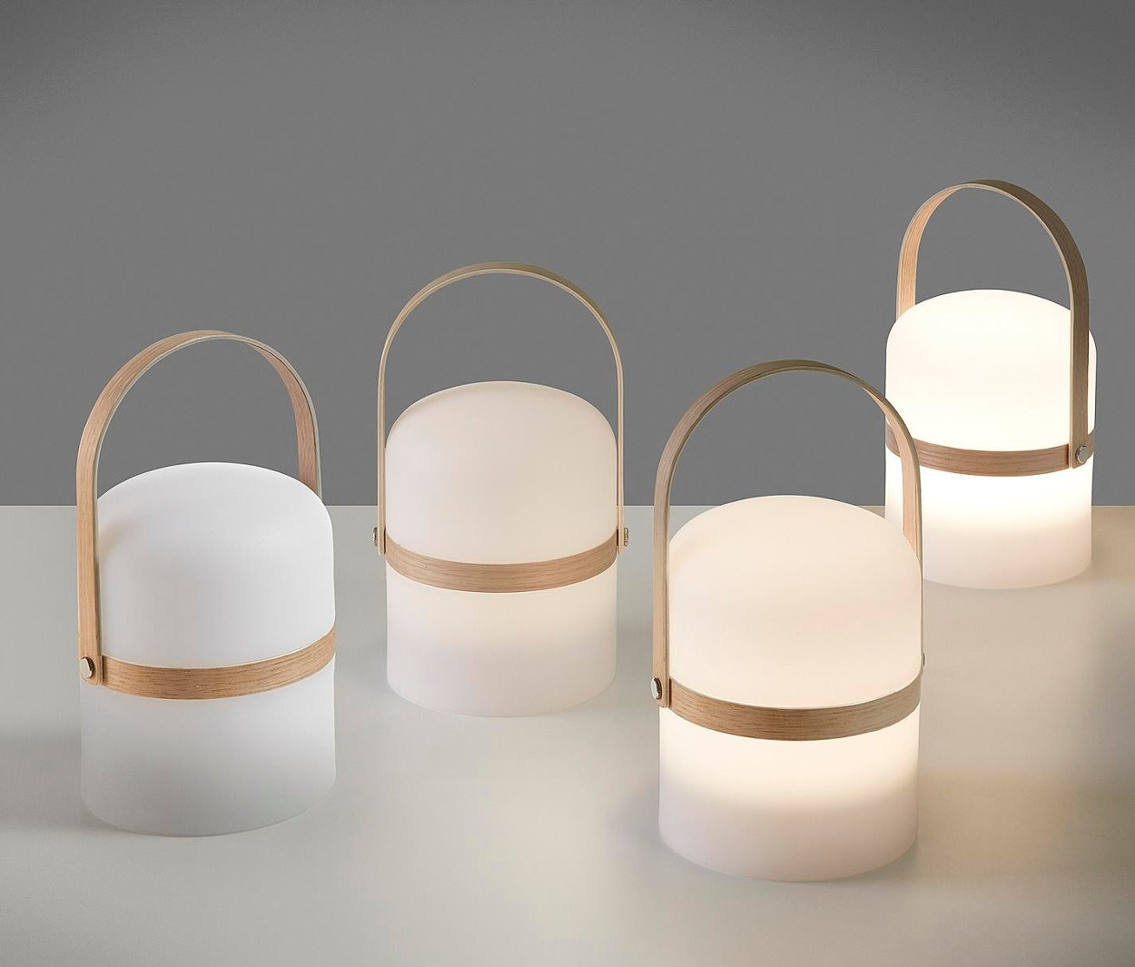 Vier Tischleuchten, naturfarben-weiß, mit Holzgriff stehen auf einem Tisch.