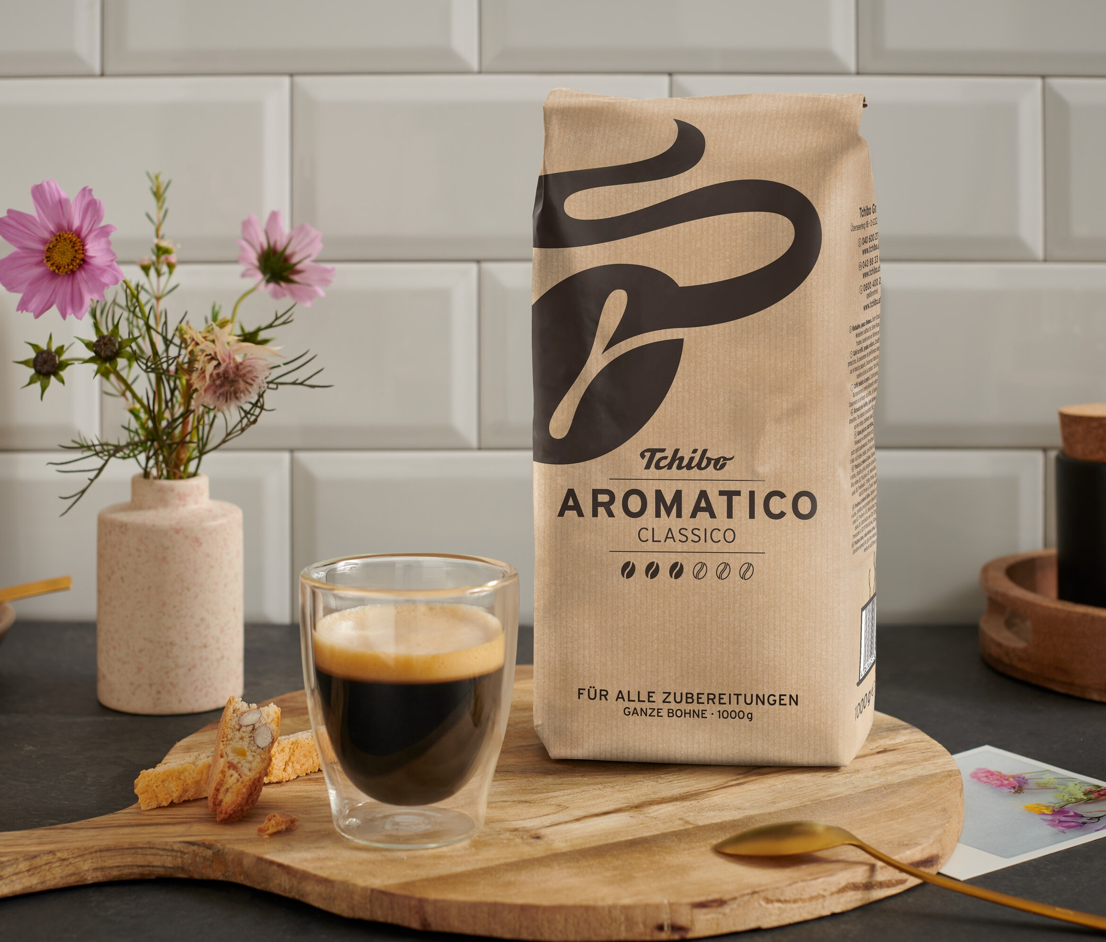 Eine Tasse Kaffee steht neben einer Packung Aromatico Classico - 1 kg Ganze Bohne auf einem Holztisch.