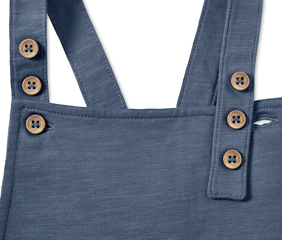 Detailaufnahme einer blauen Baby-Latzhose mit Holzknöpfen.