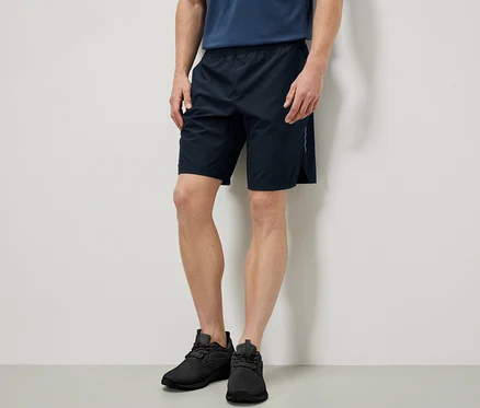 Mann steht und trägt Sportshorts.