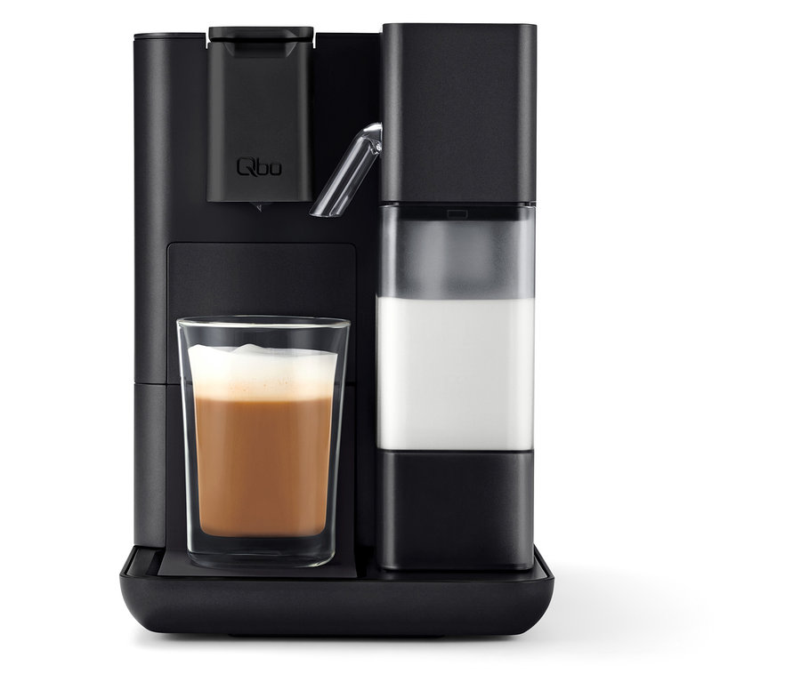 Schwarze Qbo MILK MASTER Velvet Black Kaffeemaschine mit einem Glas Milchkaffee.