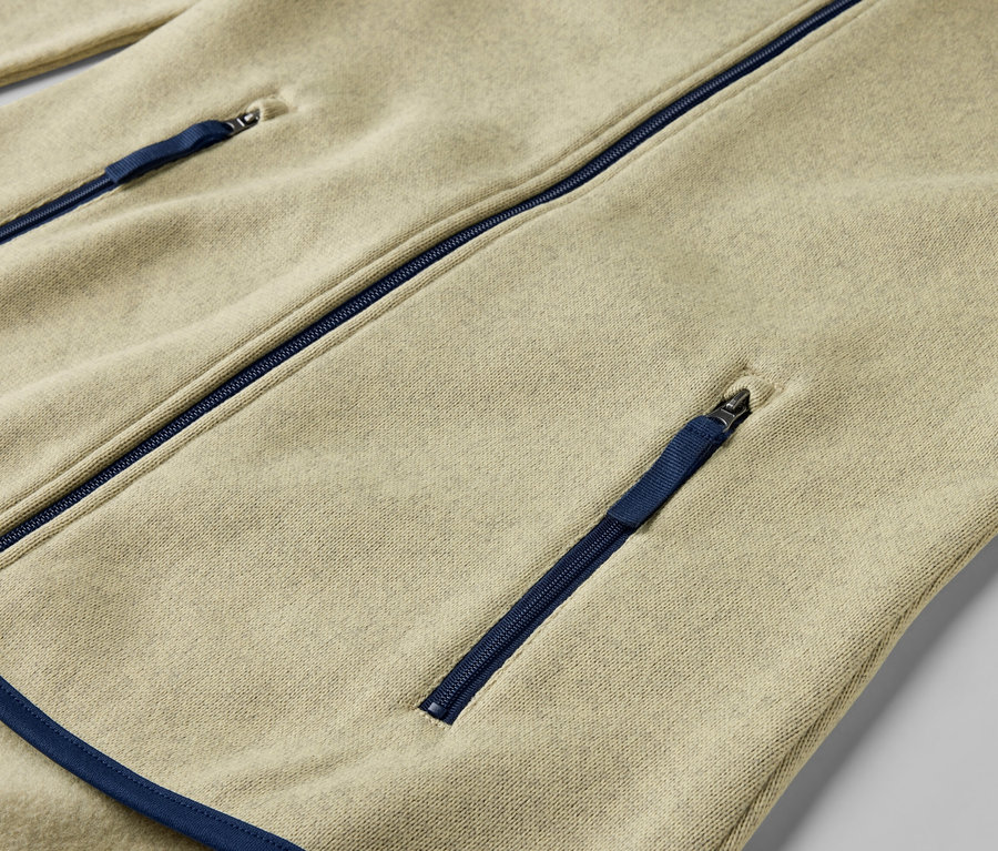 Detailansicht einer gelben Strickfleece-Jacke mit blauen Reißverschlüssen.