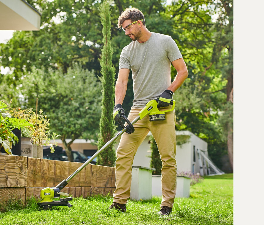 Mann trimmt Gras mit einem RYOBI 18 V One+ Akku-Rasentrimmer mit Radführung.