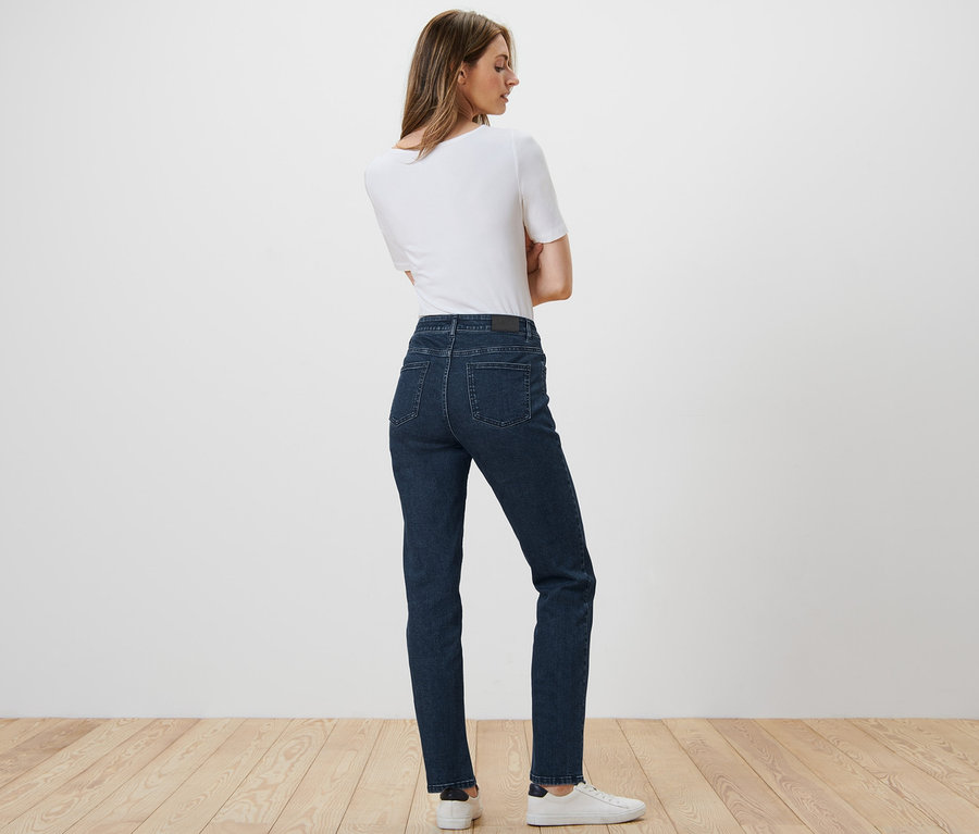 Frau posiert mit dem Rücken zur Kamera und trägt eine Straight Jeans – Fit »Kira«, ein weißes T-Shirt und Turnschuhe.