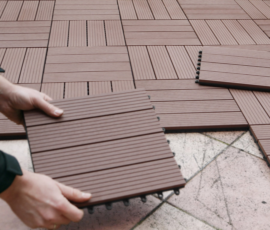 Verlegen von braunen 30 x 30 cm WPC Terrassenfliesen.