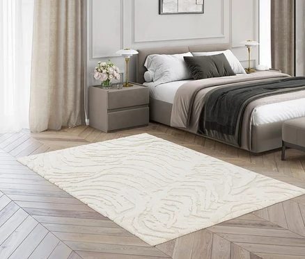 Ein cremefarbener Teppich »Cosmo« Waves liegt auf einem Holzboden in einem Schlafzimmer.