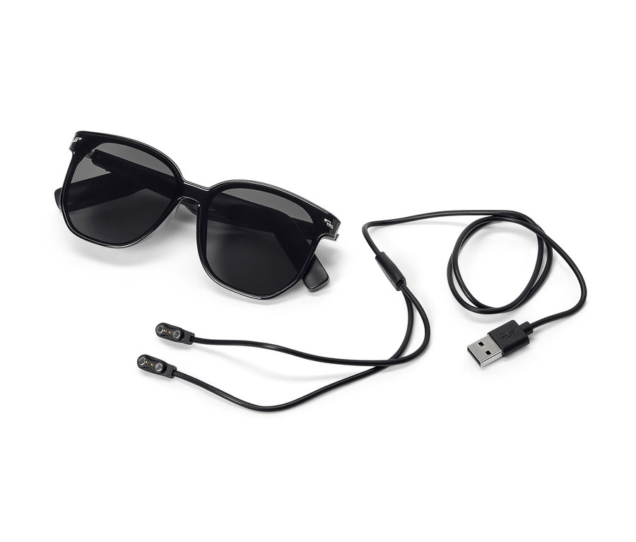 Schwarze Sonnenbrille mit Bluetooth®-Kopfhörer und Ladekabel auf weißem Hintergrund.