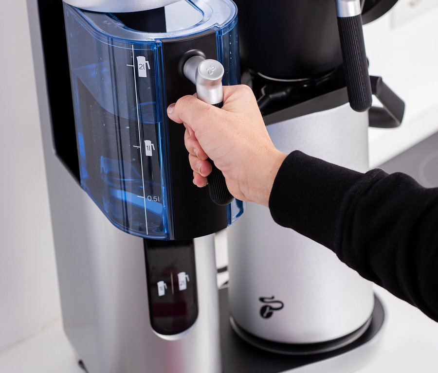 Eine Hand befüllt die Profi-Filterkaffeemaschine »Coffea Filbii«, classic silver - ohne Kanne mit Wasser.