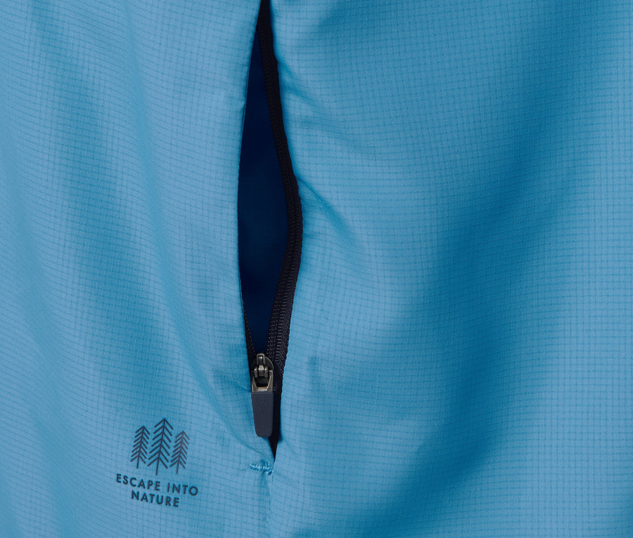 Detailansicht einer blauen Funktionsjacke, packable, mit Reißverschluss und dem Schriftzug Escape into nature.