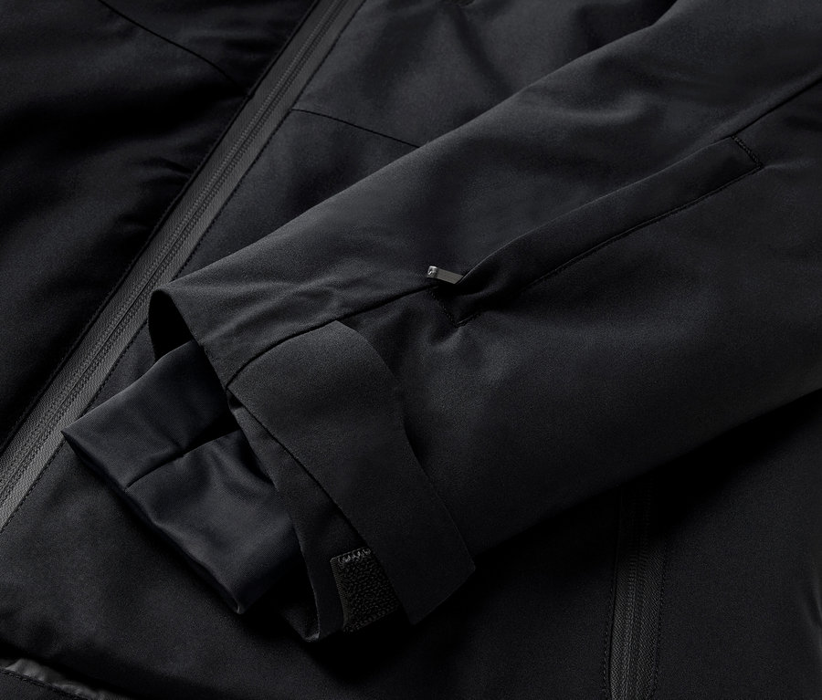 Detailaufnahme einer schwarzen Jacke mit Ärmel und Reißverschlusstasche.