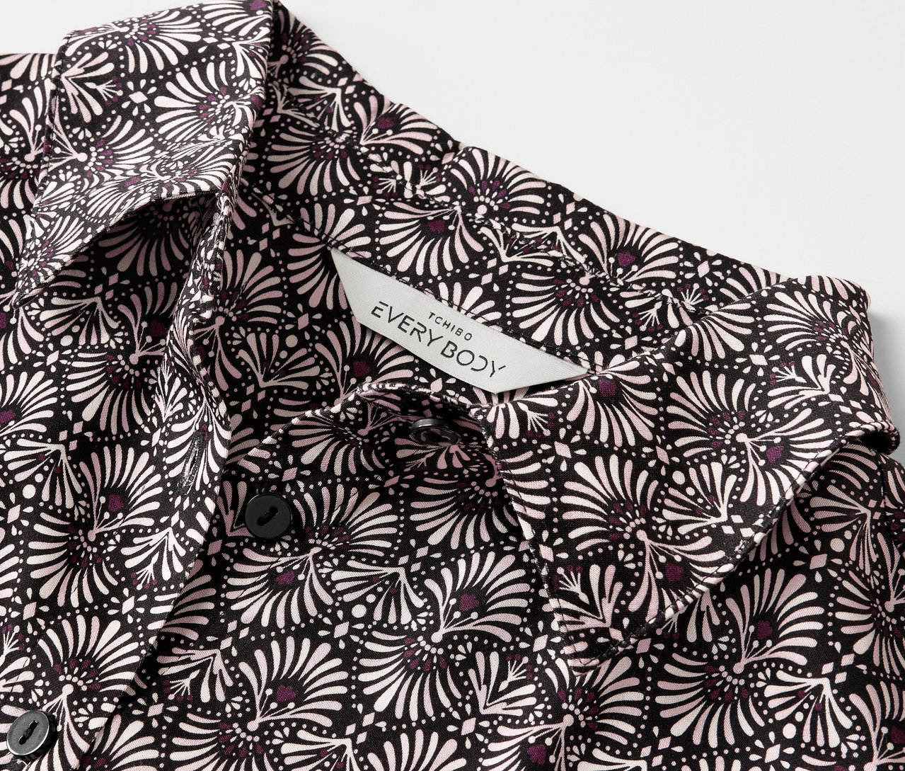 Detailansicht eines Web-Pyjamas mit schwarz-weißem Blumenmuster und Knöpfen.