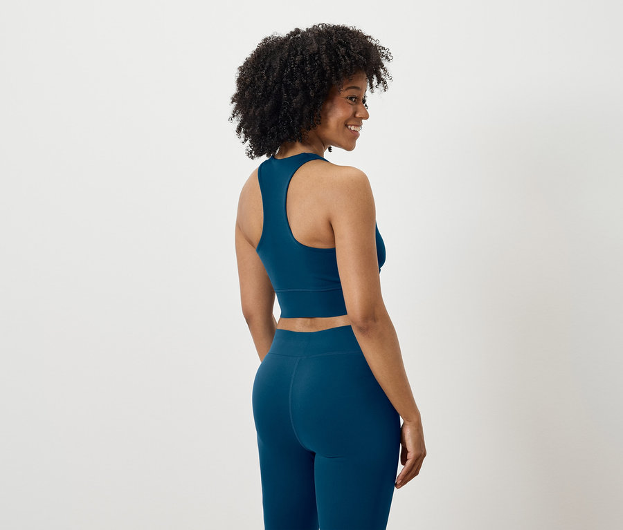 Frau blickt über die Schulter, bekleidet mit einem blauen Sport-Set.