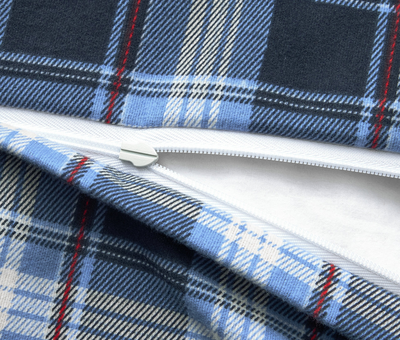 Detailaufnahme eines blau karierten Stoffes mit einem weißen Reißverschluss.