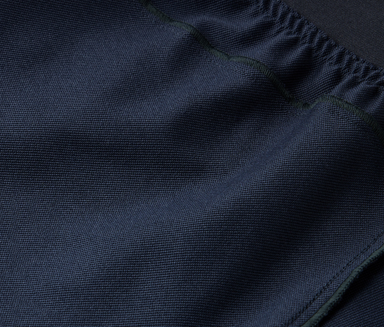 Detailaufnahme einer marineblauen Stofftextur mit Kordelzug oben.