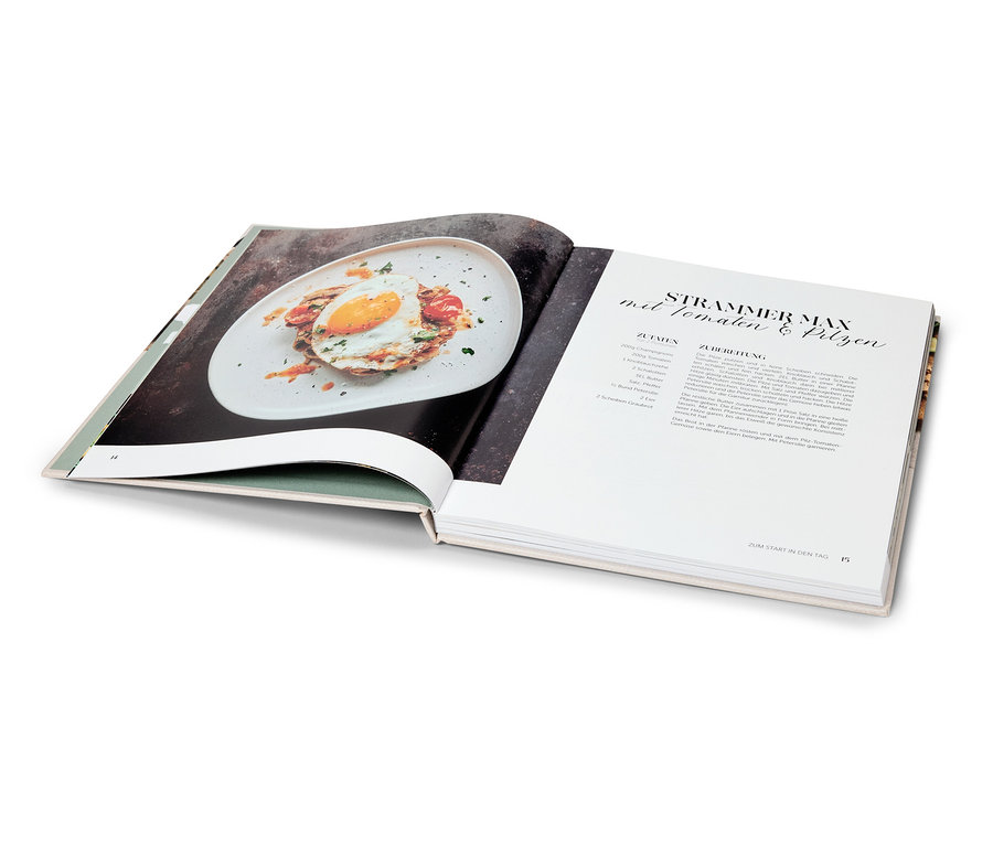 Aufgeschlagenes Kochbuch, auf einer Seite ein Foto von einem Gericht, auf der anderen Seite ein Rezept.