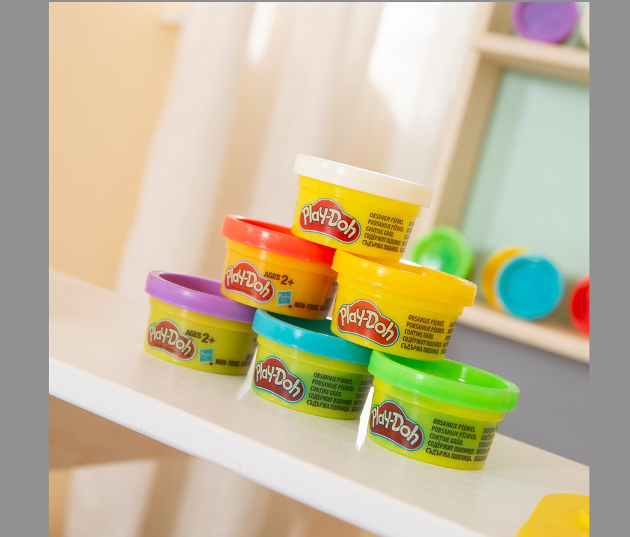 Auf einem weißen Regal steht eine Pyramide aus verschiedenfarbigen Play-Doh-Bechern.