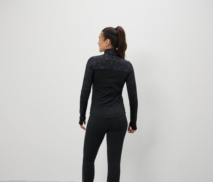 Frau mit dem Rücken zur Kamera trägt schwarze Sportbekleidung.