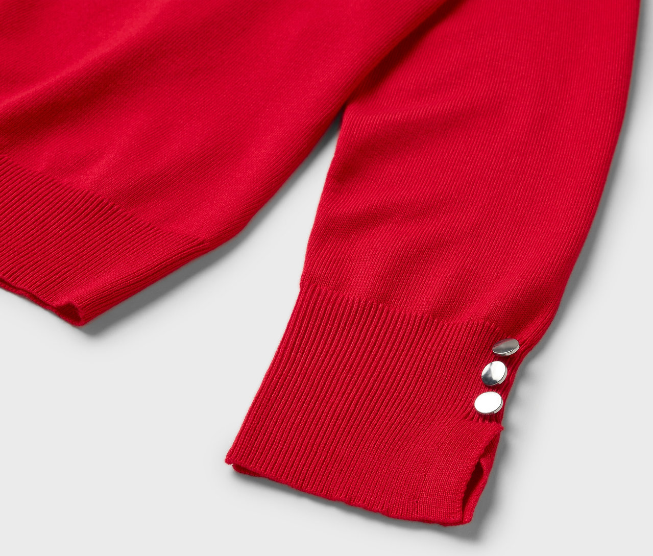 Detail eines roten Langarmpullovers mit drei silbernen Knöpfen an der Manschette.
