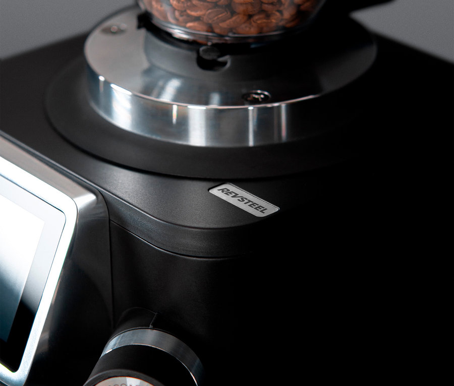 Nahaufnahme einer Kaffeemühle mit Kaffeebohnen im Behälter.