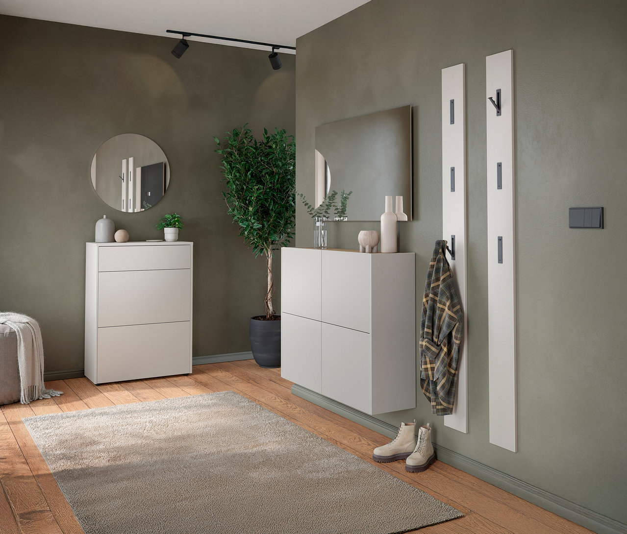 Flur mit weißen Schuhschränken, Spiegel, Garderobenpaneelen, Teppich und Topfpflanze.