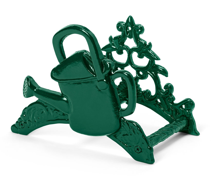 Eine grüne Miniatur-Gießkanne sitzt auf einem verzierten Halter.