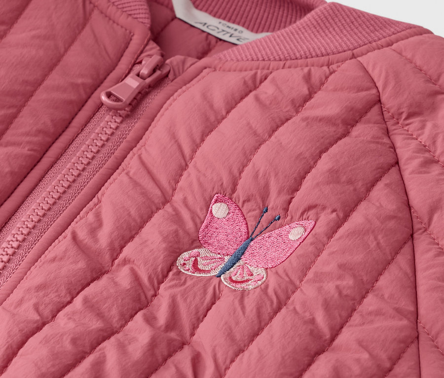 Nahaufnahme einer gesteppten, rosafarbenen Jacke mit Reißverschluss und einer gestickten Schmetterlingsapplikation.