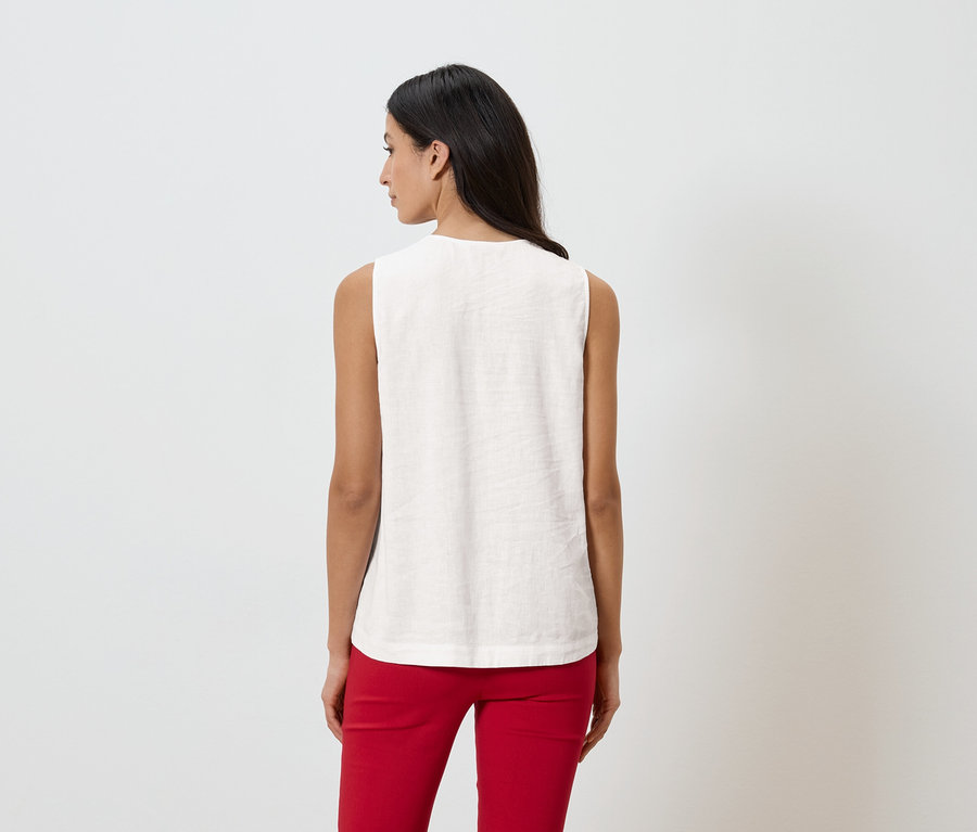 Frau von hinten in ärmellosem Oberteil und roter Hose vor weißem Hintergrund.