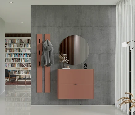 Graue Jacke hängt an einer orangefarbenen Garderobe neben einem orangefarbenen Schrank mit rundem Spiegel an einer grauen Wand.