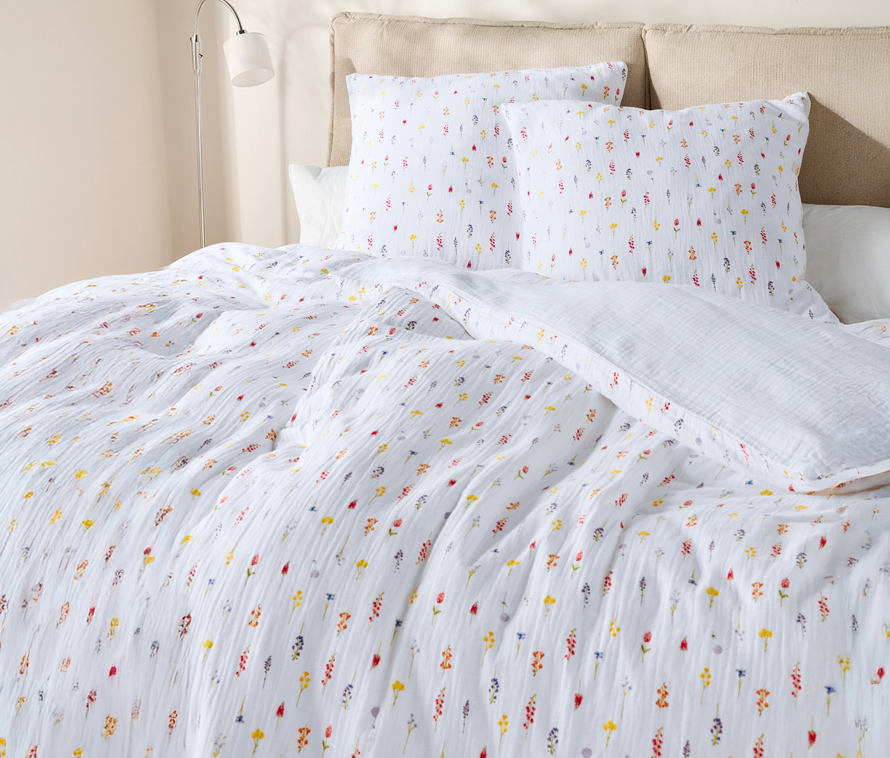 Nahaufnahme eines Bettes mit weißer Bettwäsche mit Blumenmuster und Kissen.