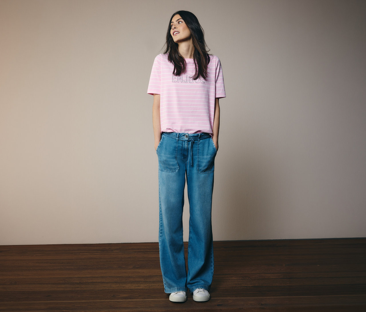 Frau mit pink gestreiftem Shirt und CECIL Jeans »Neele« steht vor der Wand.