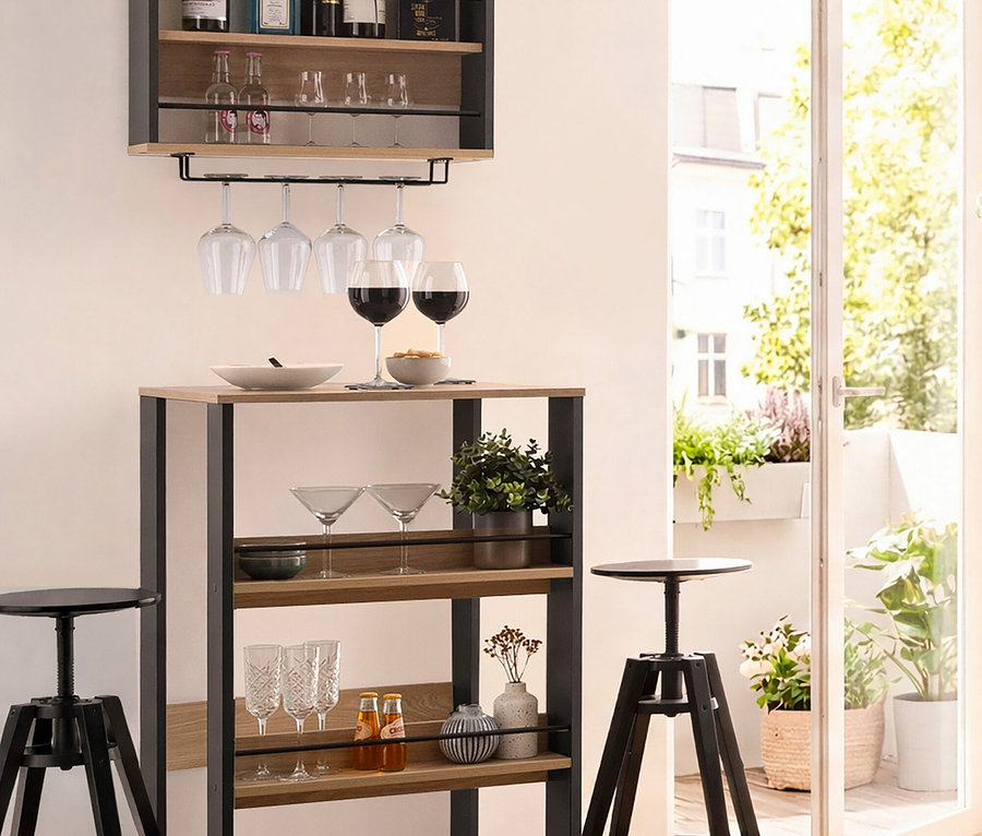 Bar mit Spirituosen und Gläsern an der Wand und auf einem Tisch, flankiert von zwei schwarzen Hockern.