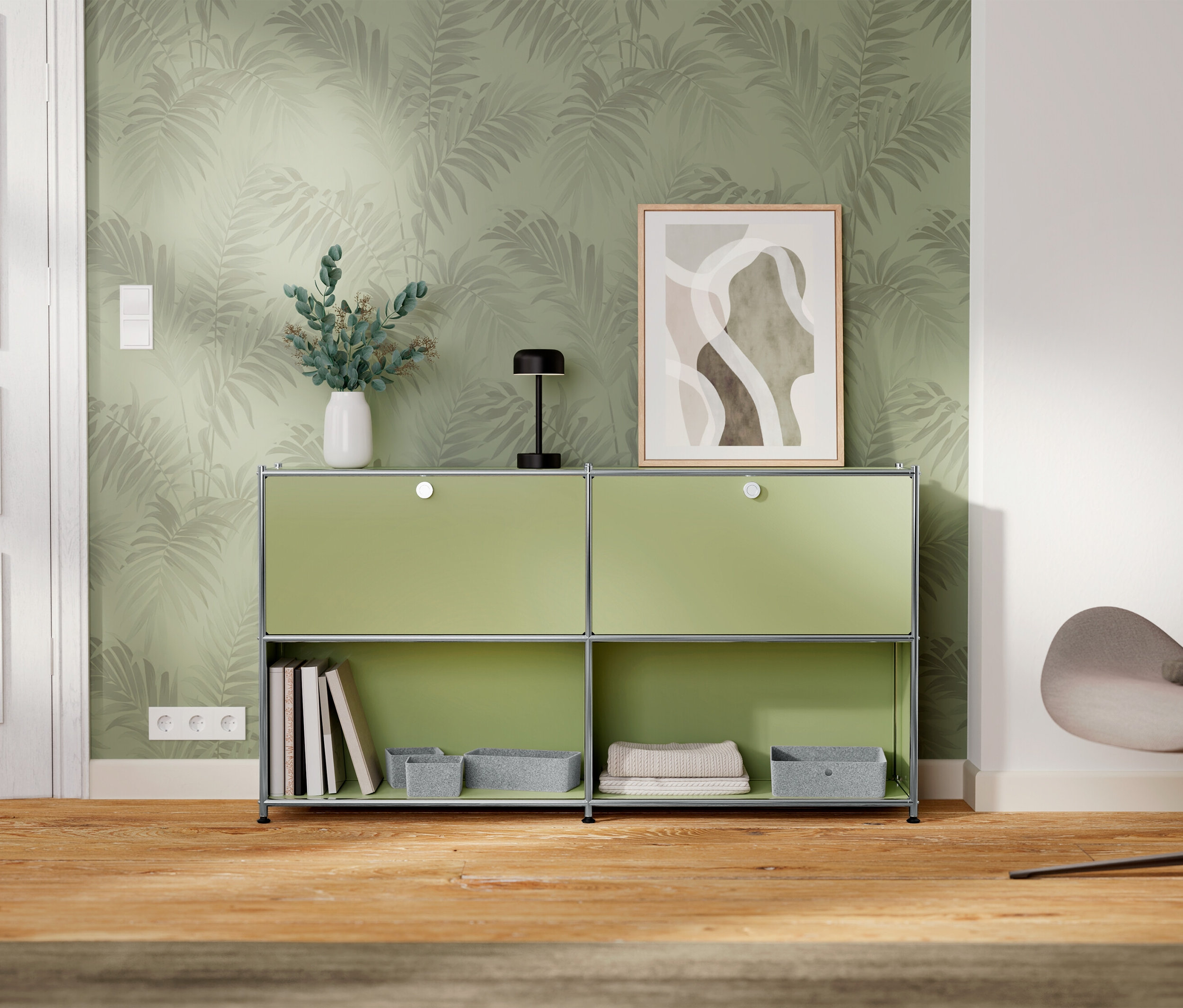 Grüner Schrank mit zwei Fächern steht an einer Wand mit Blättermuster-Tapete.